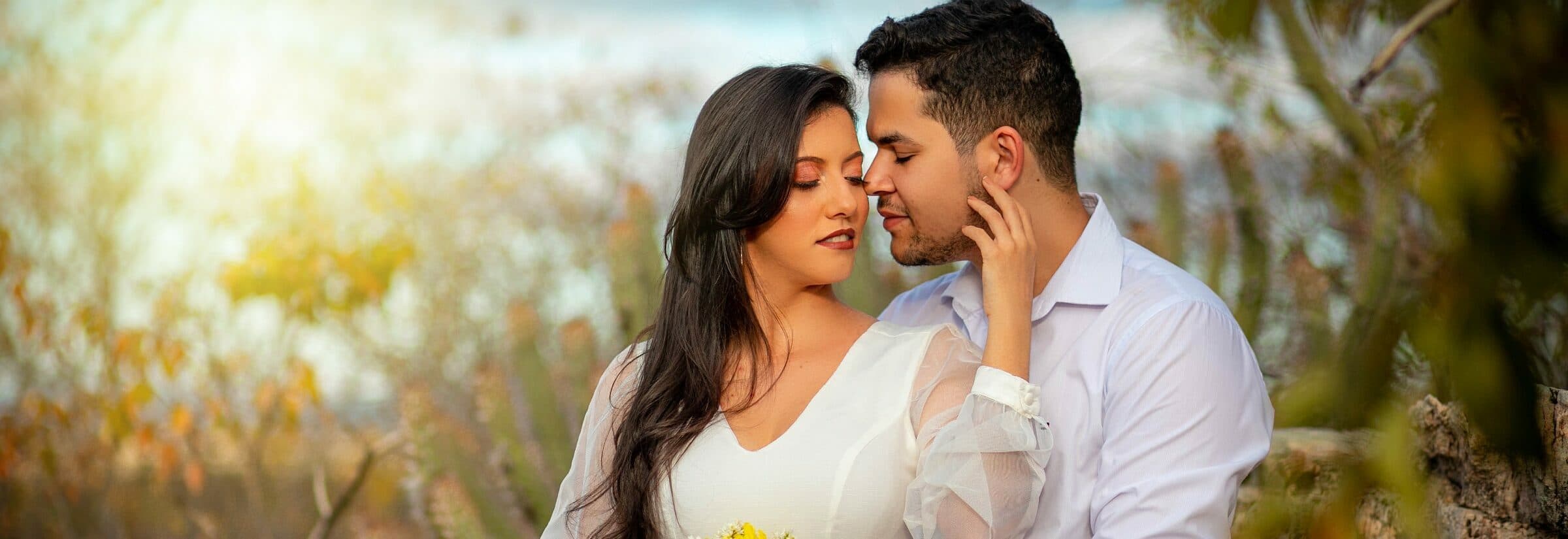 Casal de olhos fechados, abraçado em um ensaio ao ar livre.